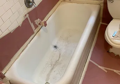 Bathtub surface before professional reglazing showing worn and stained finish