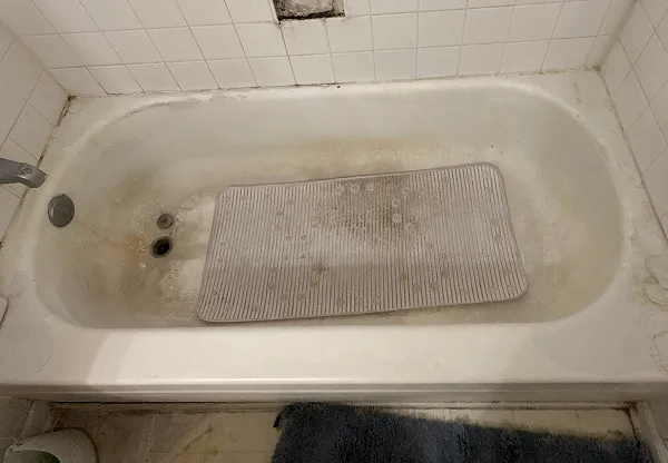 Worn bathtub with heavy stains and surface damage before professional bathtub refinishing